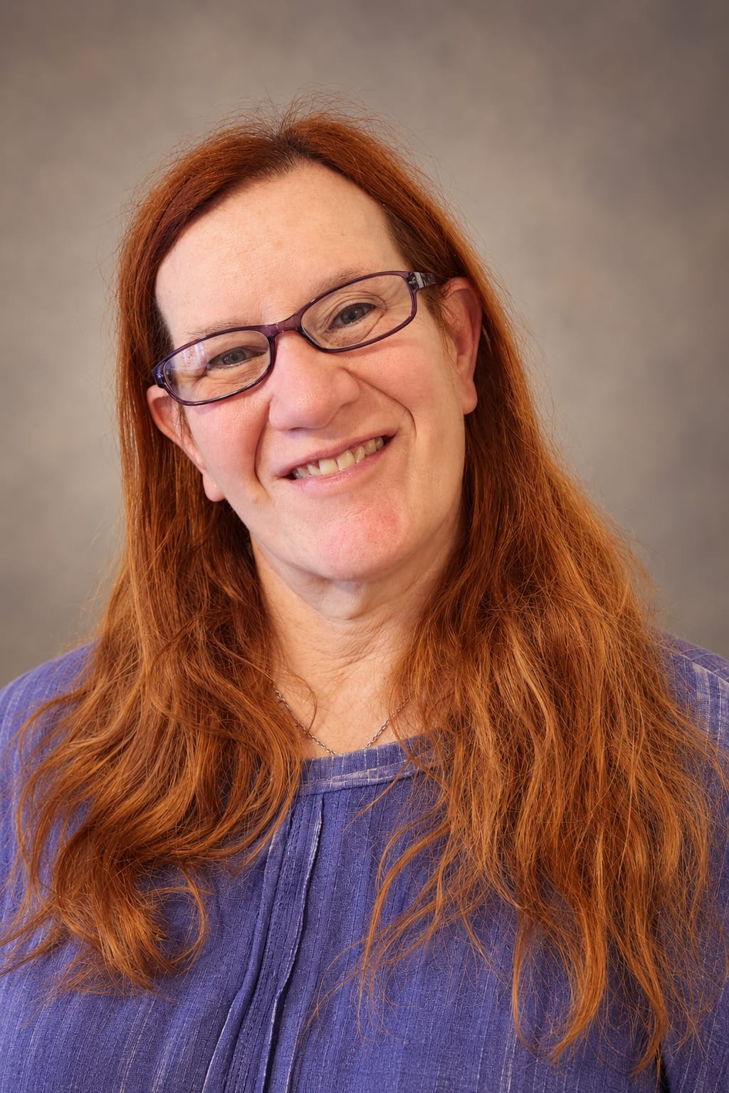 Rachel Delphine smiling, wearing purple glasses and a purple top